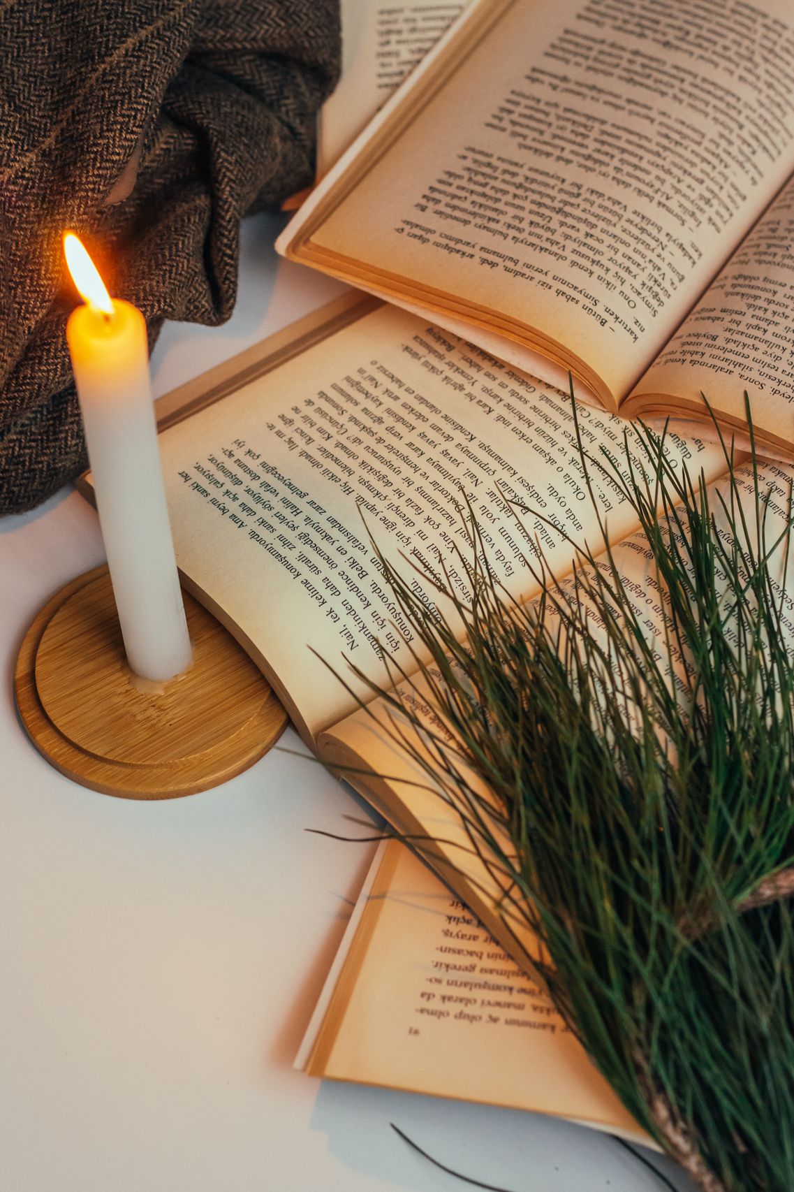 Candle on books with greenery